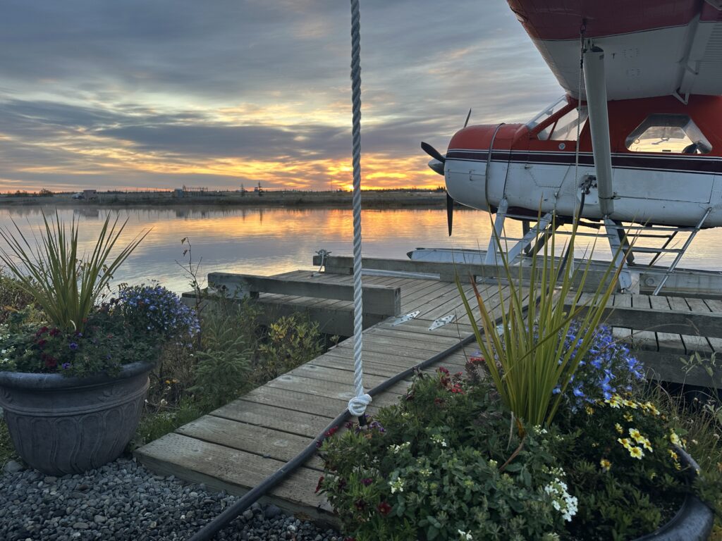 Floatplane beside a wooden dock with flower planters at sunset